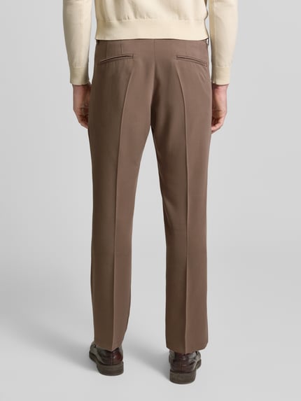 Männermodel trägt braune Straight Fit Stoffhose aus Lyocell-Mix Modell 'Leek' von Drykorn mit Bügelfalten, Ganzkörperansicht Rückansicht
