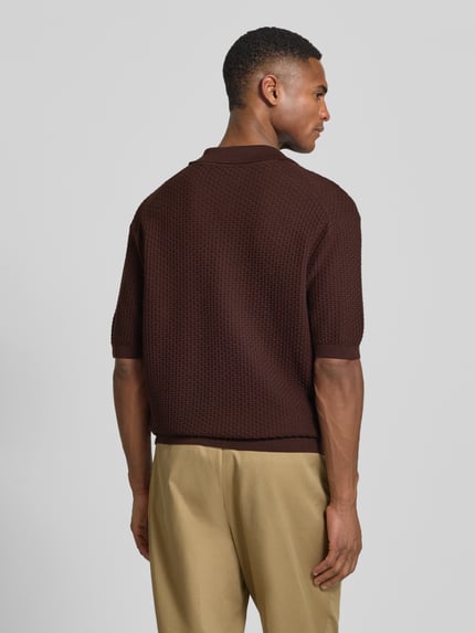 Männermodel trägt Regular Fit Poloshirt aus reiner Baumwolle Modell 'H-Natalo' von BOSS in brauner Flechtoptik, Strukturmuster, kurze Ärmel, Rippabschlüsse, Ganzkörperansicht Rückansicht.