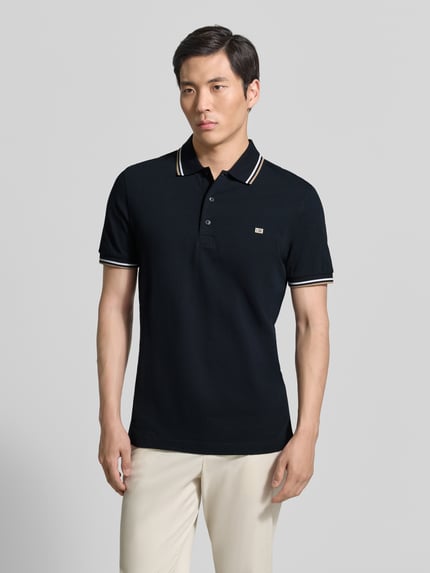 Męski model nosi Regular Fit Poloshirt mit Kontraststreifen von Christian Berg Men z bawełny, listwa guzikowa, długość tyłu 71 cm, Ganzkörperansicht von vorne.
