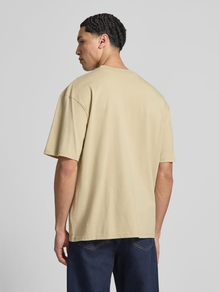 Męski model nosi Oversized Fit T-Shirt mit Logo-Stitching od Pegador, czysta bawełna, beżowy, krój oversized fit, widok całej sylwetki z tyłu.