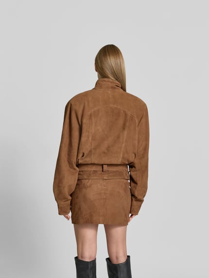 Vrouwenmodel draagt Lederjacke aus echtem Ziegenleder van ROTATE in bruin geitenleer met opstaande kraag en borstzakken, regular fit, ruglengte maat 36: 60 cm, borstwijdte maat 36: 37 cm, mouwlengte maat 36: 82 cm, geheel van achteren