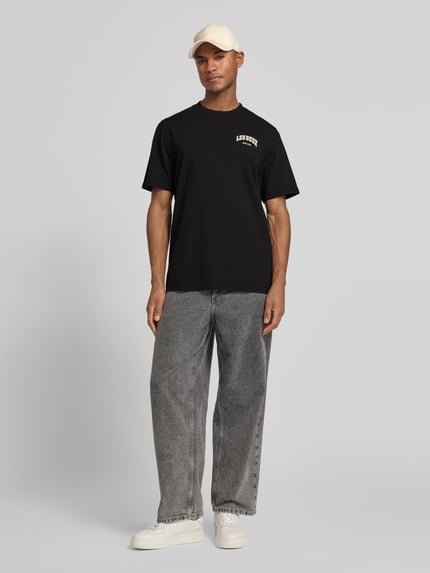 Männermodel trägt schwarzes Herren T-Shirt mit Label-Print Modell 'Brady whop' von Les Deux aus Reine Baumwolle, Gerader-Schnitt, Ganzkörperansicht von vorne.