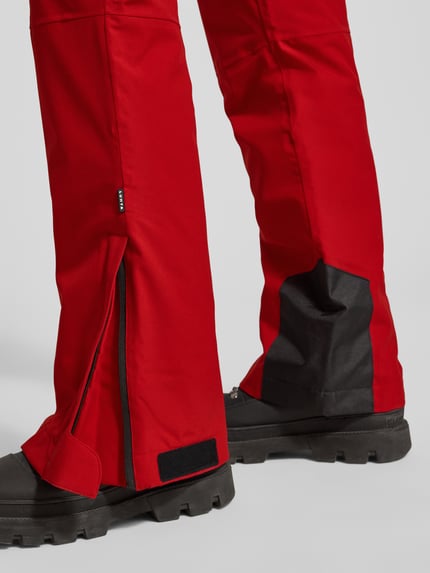 Männermodel trägt Flared Stoffhose mit Reißverschlusstaschen Modell 'KUMPULA' von LUHTA, roter Anzug-Stoff, Detailaufnahme Unterbein.