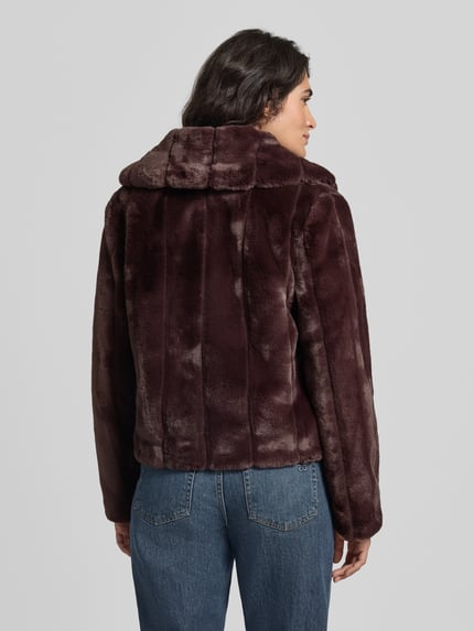 Kobiece model nosi kurtkę z sztucznego futra o kroju regular fit Model 'NEW SOPHY' od GUESS, wykładany kołnierz, długość tyłu w rozmiarze S: 58 cm, szerokość ramion w rozmiarze S: 42 cm, szerokość w rozmiarze S: 52 cm, długość rękawów w rozmiarze S: 62 cm, widoczna miękka faktura, całościowy widok z tyłu.