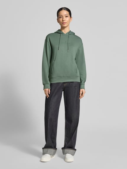 Frauenmodel trägt Hoodie mit Tunnelzug Modell 'IMA' von MSCH Copenhagen in Grün, gerade geschnitten, Ganzkörperansicht von vorne.