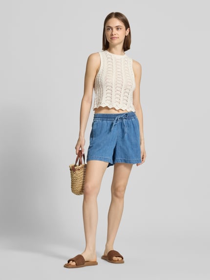 Frauenmodel trägt Shorts mit elastischer Bund und Kordelzug Modell 'RUE' von JJXX aus Leinen-Baumwoll-Mix, Loose-Fit, blaue Farbe, sichtbare Eingrifftaschen und Gesäßtaschen, Ganzkörperansicht von vorne.