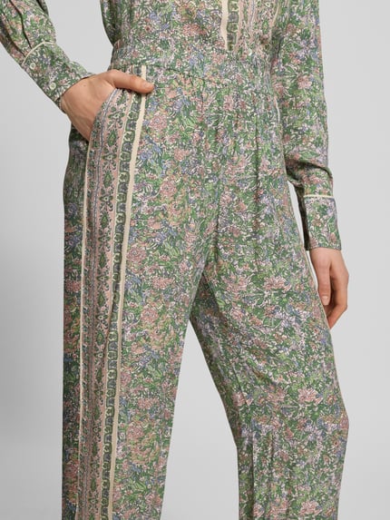 Frauenmodel trägt Stoffhose aus Viskose im Allover-Look Modell 'Bala' von MOS MOSH, grün mit floralem Muster, elastischer Bund, Nahaufnahme Oberkörper.