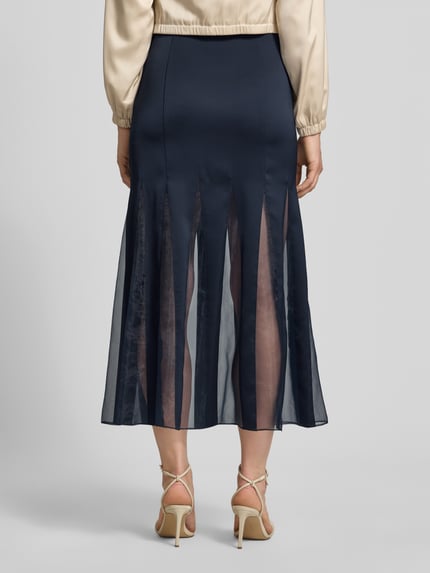 Kobiece modelka nosi długa spódnica z transparentnymi wstawkami Damen Maxi-Rock mit transparenten Einsätzen Modell 'VABELLI' von BOSS, ciemnogranatowy kolor, gładki materiał, długość maxi, widoczne tekstury, Ganzkörperansicht Rückansicht.