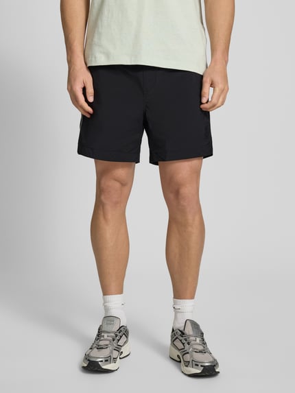 Męski model nosi Regular Fit Shorts mit Label-Applikation Modell 'COLAS262S' od HUGO, efekt: jednolity kolor, aplikacja z metką, paski w kontrastowym kolorze, elastyczny ściągacz z tunelem, wpuszczane kieszenie, krój regular fit, Ganzkörperansicht z przodu.