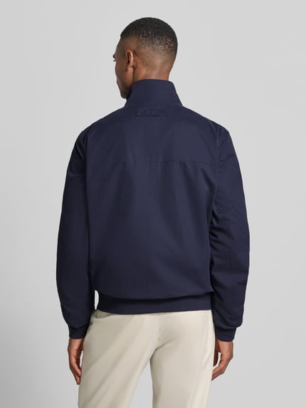 Männermodel trägt Jacke mit Stehkragen und Zweiwege-Reißverschluss von Gant, dunkelblauer Material-Mix, Regular-Fit, Eingrifftaschen, Label-Stitching, Ganzkörperansicht Rückansicht, Rückenlänge 67 cm, Schulterbreite 49 cm, Brustweite 62 cm, Ärmellänge 69 cm.