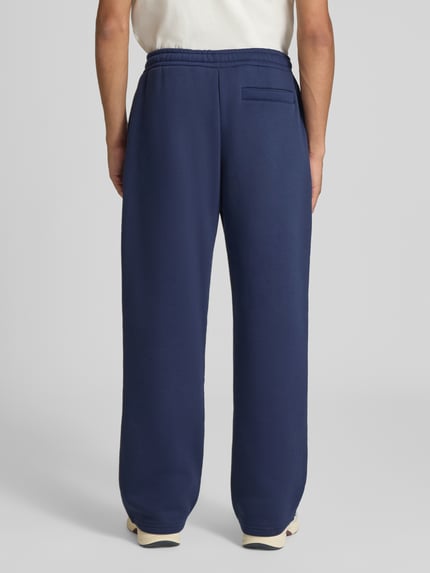 Männermodel trägt Straight Fit Sweatpants Baumwoll-Mix von REVIEW in Dunkelblau mit Gesäßtasche, Rückansicht, Ganzkörperansicht Rückansicht.