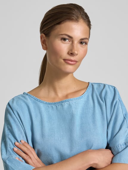 Kobiece modelka ma na sobie Relaxed Fit Bluse aus Lyocell-Mix in Denim-Optik von Christian Berg Woman, mieszanka lyocellu i bawełny, krój relaxed fit, tkanina stylizowana na denim, okrągły dekolt, rękaw o dł. 1/2, długość tyłu 56 cm, długość rękawów 31 cm, zbliżenie na górną część ciała