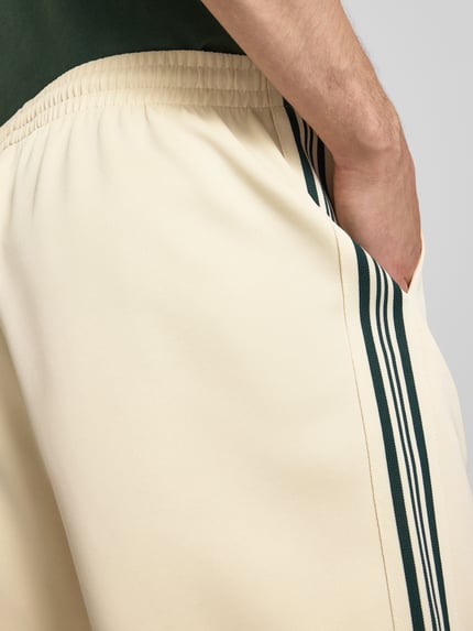 Männermodel trägt Regular Fit Sweatshorts mit elastischem Bund Modell 'RIBER' von Only & Sons in Beige mit Kontraststreifen, Nahaufnahme Oberkörper.