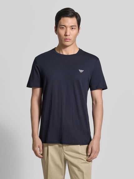 Männermodel trägt T-Shirt mit Logo-Patch und Rundhalsausschnitt von Emporio Armani in Dunkelblau, Modern Fit, glatte Baumwolle, Ganzkörperansicht von vorne.