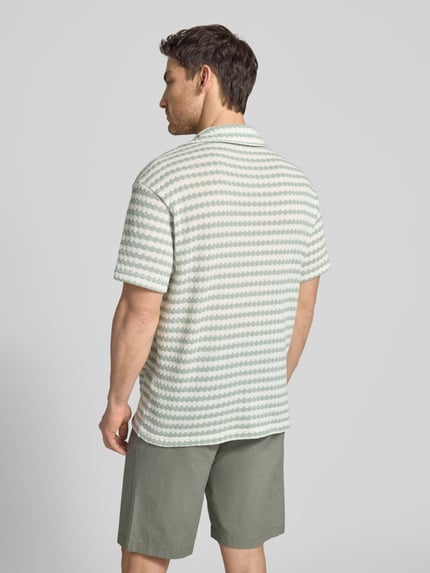 Męski model nosi Relaxed Fit Poloshirt aus Baumwoll-Mix Modell 'DYLAN' von SELECTED HOMME, efekt: wzór na całej powierzchni, krótki rękaw, kołnierz z połami, dekolt w serek, listwa guzikowa, drobny splot, mieszanka bawełny, Ganzkörperansicht Rückansicht.