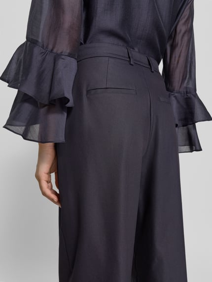 Vrouwenmodel draagt stoffen broek met biezen en steekzakken van comma, katoenmix met stretch, straight fit, detailopname achterkant.