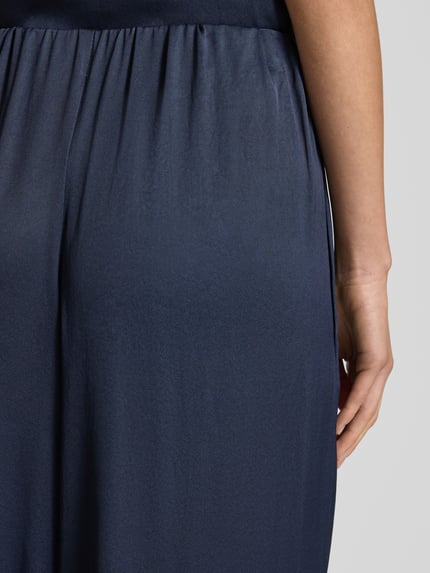 Frauenmodel trägt Hose mit weitem Bein Modell 'TWEEZER' von Drykorn in Dunkelblau, elastischer Bund, Material-Mix, Nahaufnahme Rückansicht.