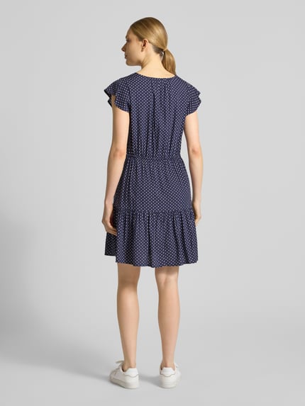Frauenmodel trägt Minikleid aus reiner Viskose mit V-Ausschnitt von GAP, taillierte Passform, Tunnelzug, kurzärmelig, blau mit Muster, Ganzkörperansicht Rückansicht.