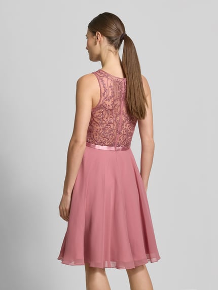 Frauenmodel trägt Cocktailkleid mit Rundhalsausschnitt von Luxuar in Altrosa mit blickdichtem Unterrock, tailliert, Ganzkörperansicht Rückansicht.