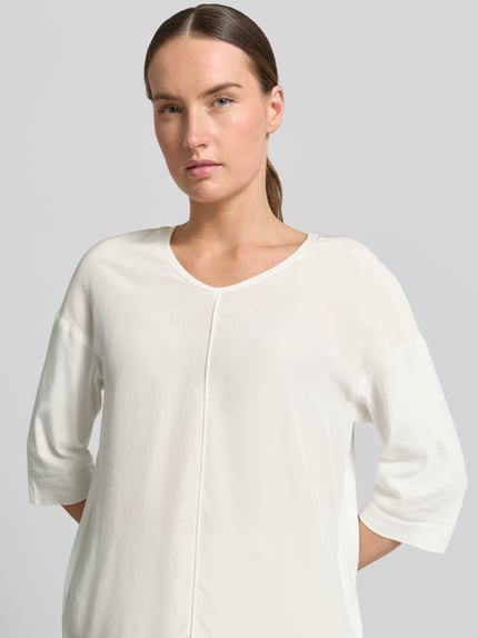 Frauenmodel trägt T-Shirt mit Ärmelaufschlag und Rundhalsausschnitt von Marc Cain, Damen T-Shirt aus Baumwoll-Mix mit Stretch-Anteil, Label-Detail, Straight Fit, Rückenlänge bei Größe 36: 62 cm, helle Farbe, schlichte Struktur, Nahaufnahme Oberkörper.