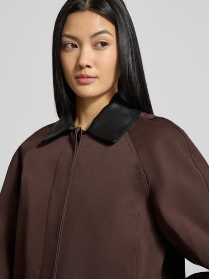 Modelka kobieca nosi Trenchcoat mit Umlegekragen und verdeckter Knopfleiste od Staud w kolorze brązowym, bawełniany mix, zbliżenie na górną część ciała.