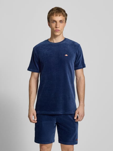 Männermodel trägt T-Shirt mit Logo Modell 'MADORI' von Ellesse aus Baumwoll-Mix mit Stretch-Anteil, Regular-Fit, Rundhalsausschnitt, Logo, Ganzkörperansicht von vorne.