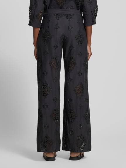 Frauenmodel trägt Hose aus Baumwolle mit Häkelspitze Modell 'MIKE' von Bash in Schwarz, Flared-Cut, Lochmuster, Ganzkörperansicht Rückansicht.