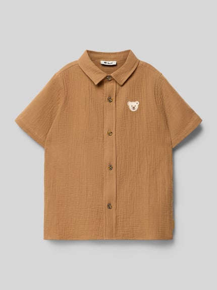 Productfoto, Regular Fit vrijetijdsoverhemd met logodetail van Steiff, puur katoen, platte kraag, korte mouw, zandkleurige kreuktextuur. Context: Kinderen vrijetijdsoverhemd van Steiff, puur katoen, regular fit, logodetail, platte kraag, met korte mouwen, ruglengte maat 116: 39 cm, schouderbreedte maat 116: 25 cm, mouwlengte maat 116: 18 cm.