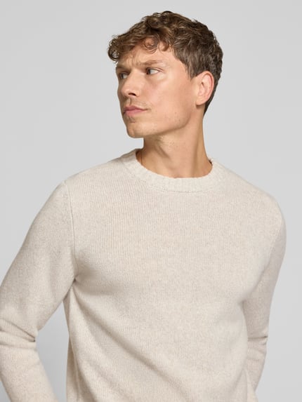 Męski model nosi Strickpullover aus Schurwolle mit Rundhalsausschnitt von MAERZ Muenchen, krój regular fit, beż, okrągły dekolt, Nahaufnahme górnej części ciała. Długość tyłu w rozmiarze 50: 65 cm, długość rękawów w rozmiarze 50: 68 cm.