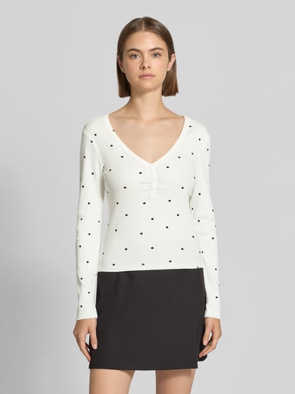 Frauenmodel trägt Regular Fit Langarmshirt aus Baumwoll-Mix Modell 'FENJA' von ONLY, weiß mit schwarzen Punkten, Ganzkörperansicht von vorne, Damen Langarmshirt von ONLY.