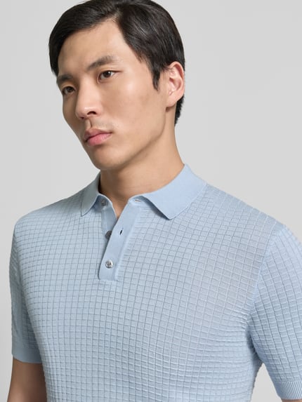Männermodel trägt Slim Fit Poloshirt in Strick-Optik Modell 'Vanceo' von JOOP! Collection aus reiner Baumwolle, Nahaufnahme Oberkörper.