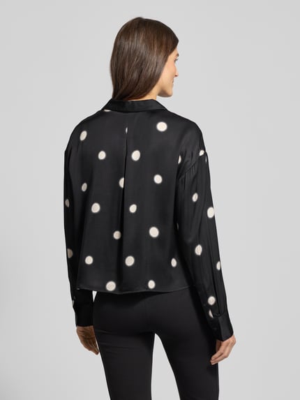 Frauenmodel trägt Hemdbluse mit Knopfleiste Modell 'Famena' von OPUS in Schwarz mit weißen Punkten, reine Viskose, lockerer Schnitt, Ganzkörperansicht Rückansicht.