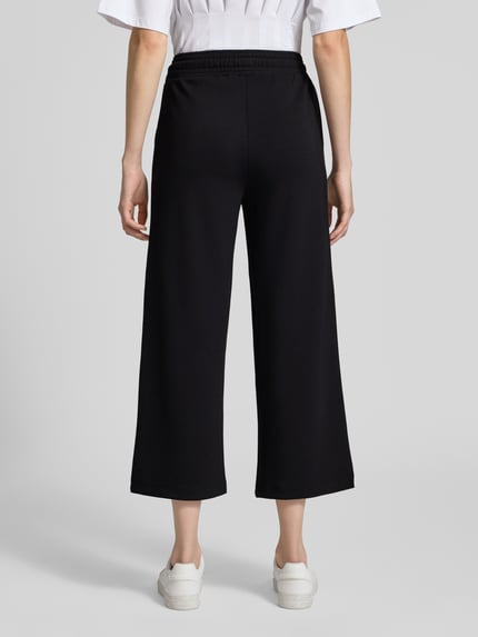 Vrouwenmodel draagt Wide Fit Sweatpants in verkorte pasvorm model 'Banu' van Soyaconcept, elastische materiaalmix met modal, wide fit, elastische band met tunnelkoord, effen zwart, zachte textuur, cropped, dames sweatpants, ganzebodyaanzicht achterkant