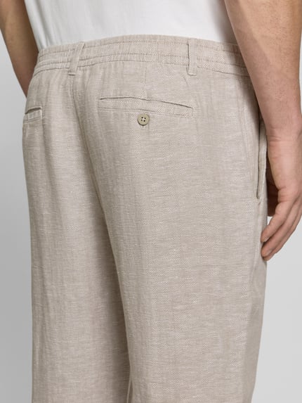 Männermodel trägt Cropped Hose aus Leinen-Baumwoll-Mix von JAKE*S STUDIO MEN im Allover-Look mit Eingrifftaschen, Detailaufnahme Rückansicht.