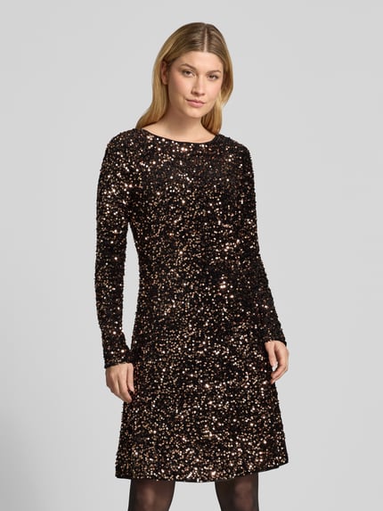 Frauenmodel trägt Knielanges Kleid mit Pailletten von Christian Berg Woman Selection, schwarzer Stoff mit silberner Paillettenstruktur, gerader Schnitt, Rundhalsausschnitt, lange Ärmel, Ganzkörperansicht von vorne.