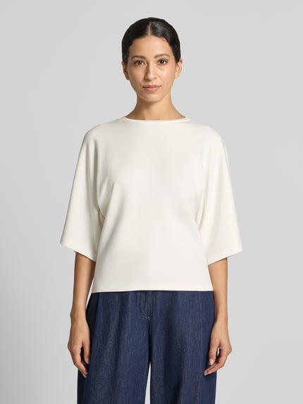 Frauenmodel trägt Relaxed Fit Sweatshirt aus elastischem Modal-Mix Modell 'Unora' von someday., cremeweiß, 1/2-Arm, Rundhalsausschnitt, glatte Textur, lockere Passform, Ganzkörperansicht von vorne.