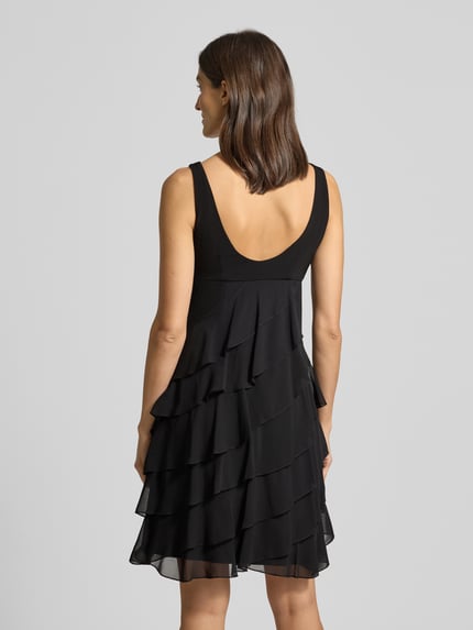 Vrouwenmodel draagt Knielanges Cocktailkleid met Volants van Swing, zwarte chiffon, A-lijn, knielengte, ronde hals, ruglengte maat 36: 103 cm, borstwijdte maat 36: 31 cm. Ganzkörperansicht Rückansicht.