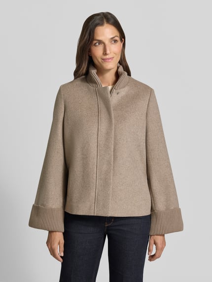 Vrouwenmodel draagt Jacke aus Woll-Mix met gestricktem Stehkragen van comma, beige tint, wolmix met viscose, loose fit, steekzakken, gebreide mouwboorden, ritssluiting en drukknoopsluiting, ruglengte maat 36: 62 cm, schouderbreedte: 36 cm, borstwijdte: 53 cm, mouwlengte: 64 cm, frontaal volledig lichaam.