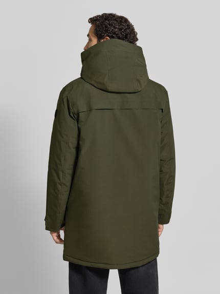 Męski model nosi Parka mit Kapuze und Pattentaschen Modell 'AIDEN' od Didriksons, kolor ciemna zieleń, krój regular fit, Kaptur, zamek błyskawiczny zakryty, kieszenie z patką, Długość tyłu w rozmiarze M: 95 cm, szerokość ramion w rozmiarze M: 47 cm, szerokość w klatce piersiowej w rozmiarze M: 55 cm, Długość rękawów w rozmiarze M: 68 cm, widok całej sylwetki z tyłu.
