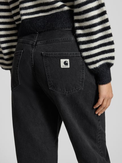Frauenmodel trägt Jeans mit weitem Bein Modell 'Brandon' von Carhartt Work In Progress aus reiner Baumwolle mit Eingrifftaschen, Nahaufnahme Rückansicht.