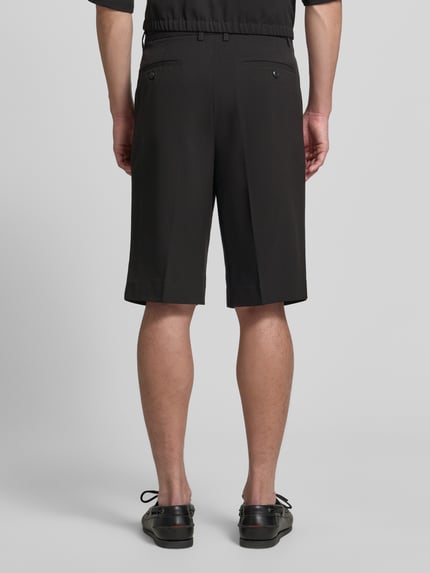 Mężczyzna nosi Straight Fit Shorts mit Viskose-Anteil od Lindbergh, czarna tkanina z zakładkami, tylne kieszenie, szerokość w rozmiarze M: 44 cm, długość nogawki wewnętrznej: 30 cm, widok całej sylwetki z tyłu.