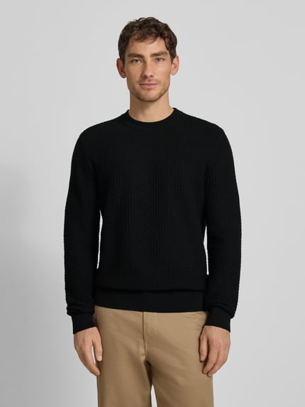 Männermodel trägt Regular Fit Strickpullover aus reiner Baumwolle Modell 'IMBERTO' von BOSS, unifarben, Strukturmuster, Ganzkörperansicht von vorne.