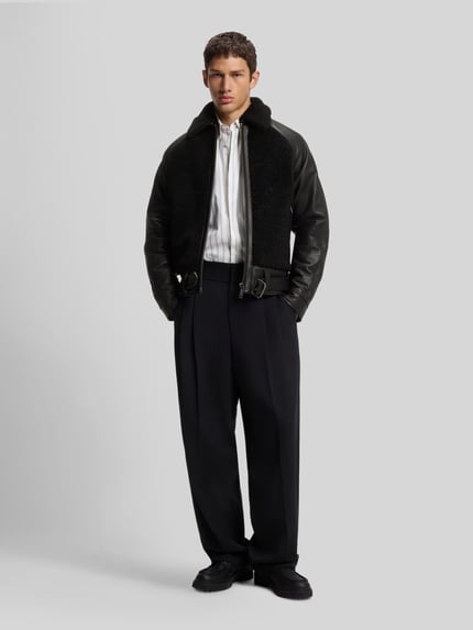 Männermodel trägt Lederjacke Modell 'Laran' mit Schnalle von HUGO, unifarbene Optik, Glattleder, Struktur, Ganzkörperansicht von vorne.