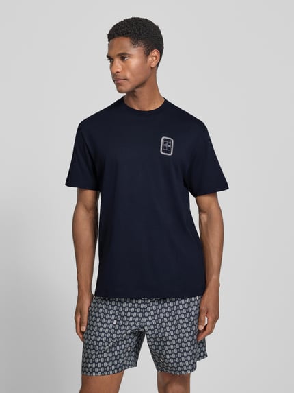 Männermodel trägt dunkelblaues Regular Fit T-Shirt aus reiner Baumwolle Modell 'CN Tenniscourt Backprint' von Lacoste, Ganzkörperansicht von vorne, Herren T-Shirt.