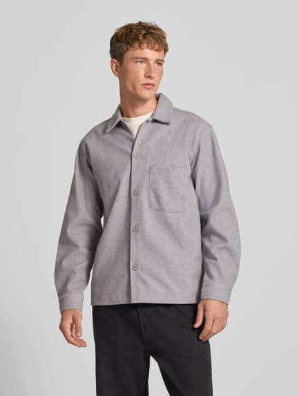 Męski model nosi Regular Fit Hemdjacke mit Kentkragen Modell 'REGENT' od JACK & JONES w szarym kolorze, gładka faktura, listwa guzikowa, całkowity widok z przodu; długość tyłu w rozmiarze M: 72 cm, szerokość ramion w rozmiarze M: 50 cm, długość rękawów w rozmiarze M: 64 cm.