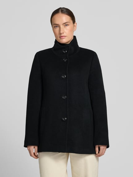 Frauenmodel trägt Jacke mit Stehkragen und Eingrifftaschen von FUCHS SCHMITT in Schwarz, Material-Mix mit Woll-Anteil, Knopfleiste, A-Linie, Ganzkörperansicht von vorne.
