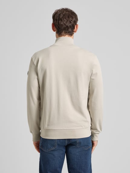 Męski model nosi Sweatjacke mit Stehkragen und Reißverschluss od Colmar Originals z bawełny, krój regular fit, beżowy, długość tyłu 70 cm, długość rękawów 65 cm, całe ciało widziane z tyłu.