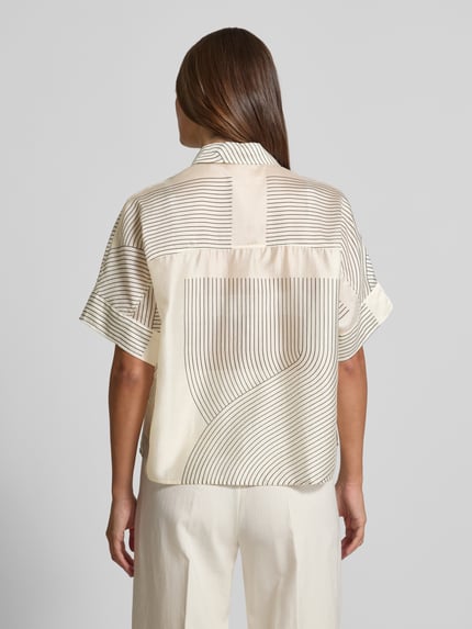 Frauenmodel trägt Boxy Fit Bluse aus Lyocell-Mix Modell 'Zulin' von Someday, cremefarben mit schwarzen Linien, Ganzkörperansicht Rückansicht. Rückenlänge bei Größe 36: 60 cm, Ärmellänge bei Größe 36: 20 cm, Hemdblusenkragen, verdeckte Knopfleiste.