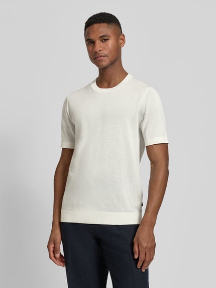 Männermodel trägt Strickshirt mit Rundhalsausschnitt und 1/2-Arm von OLYMP Level Five in Weiß, Baumwoll-Lyocell-Mix, Regular-Fit, Rückenlänge 67 cm, Ganzkörperansicht von vorne.