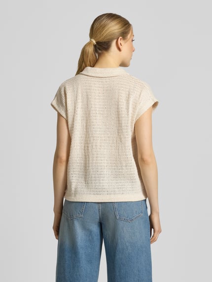 Frauenmodel trägt Strickshirt mit Polokragen und V-Ausschnitt Modell 'Somona' von OPUS aus Baumwoll-Elasthan-Mix, Regular-Fit, Rückenlänge 55 cm, Ärmellänge 12 cm, Strukturstrick in Beige, Ganzkörperansicht Rückansicht.